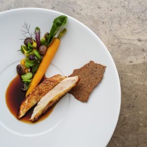 Hähnchengericht mit Karotte und brauner Sauce auf einem weißen Teller.
