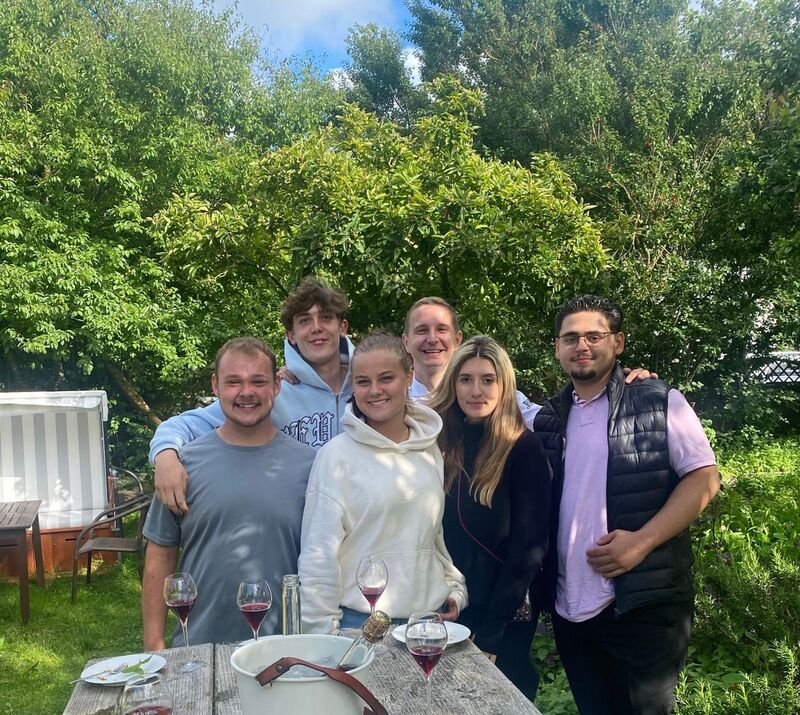 Sechs Freunde beim Essen im Freien im Söl’ring Hof, Urlaub auf Sylt.