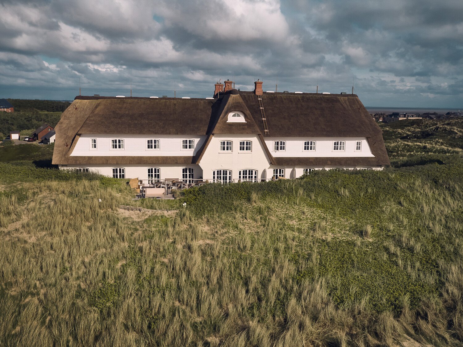 Söl’ring Hof, Sylt: Weißes Reetdachhaus inmitten der Dünen, erholsamer Urlaub.