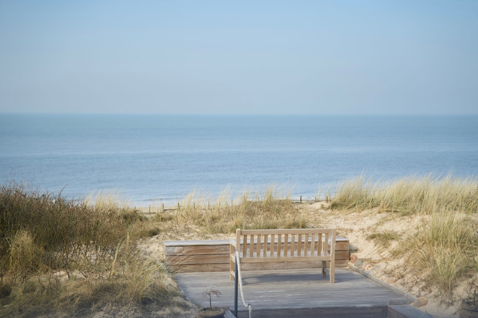 Eine Bank auf dem Deck, Dünen, das Meer – wie im „Söl’ring Hof Sylt“.