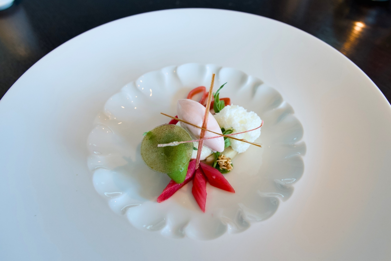 Artfully plated veggies, white mousse, pink cream, thin sticks.