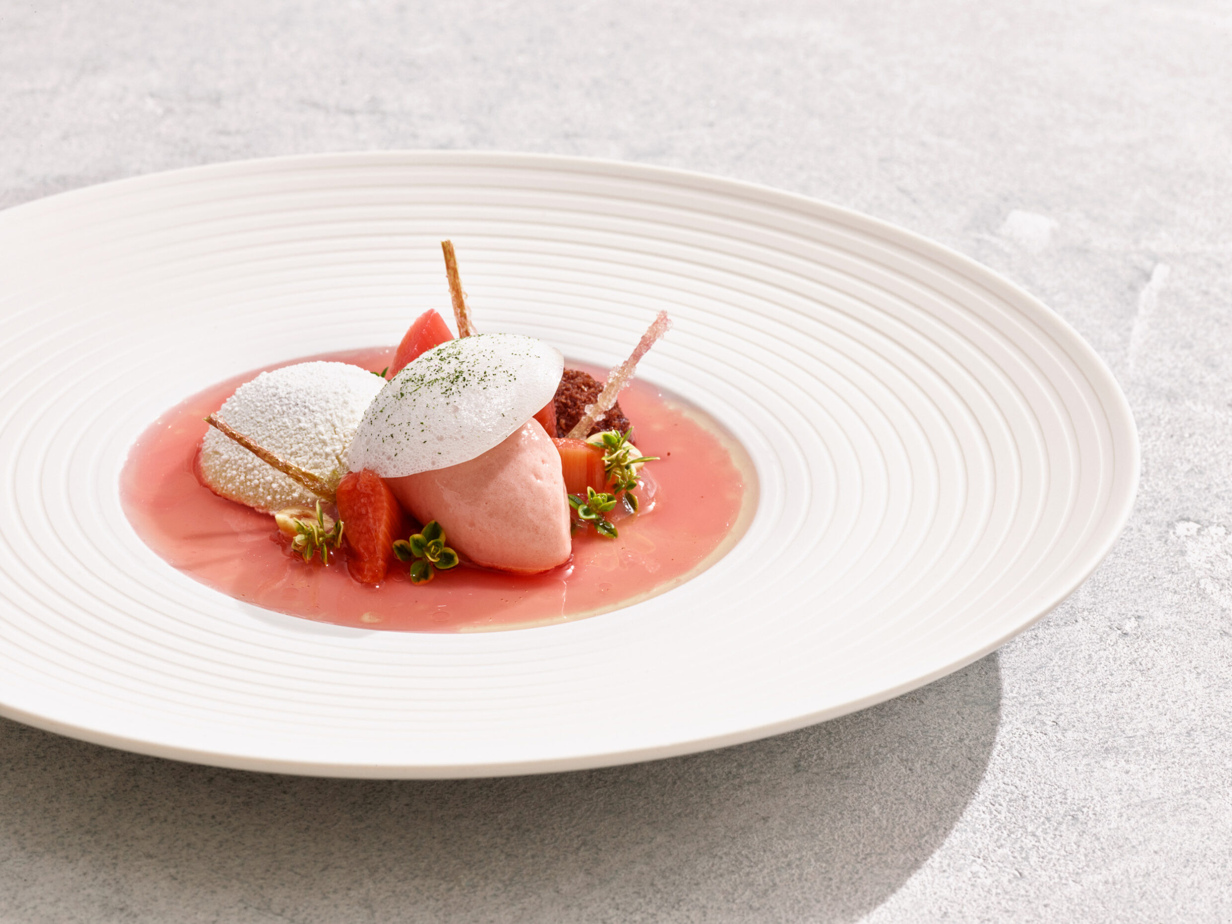 Pink sorbet, powdered sphere, crispy sticks, flowers on white plate.