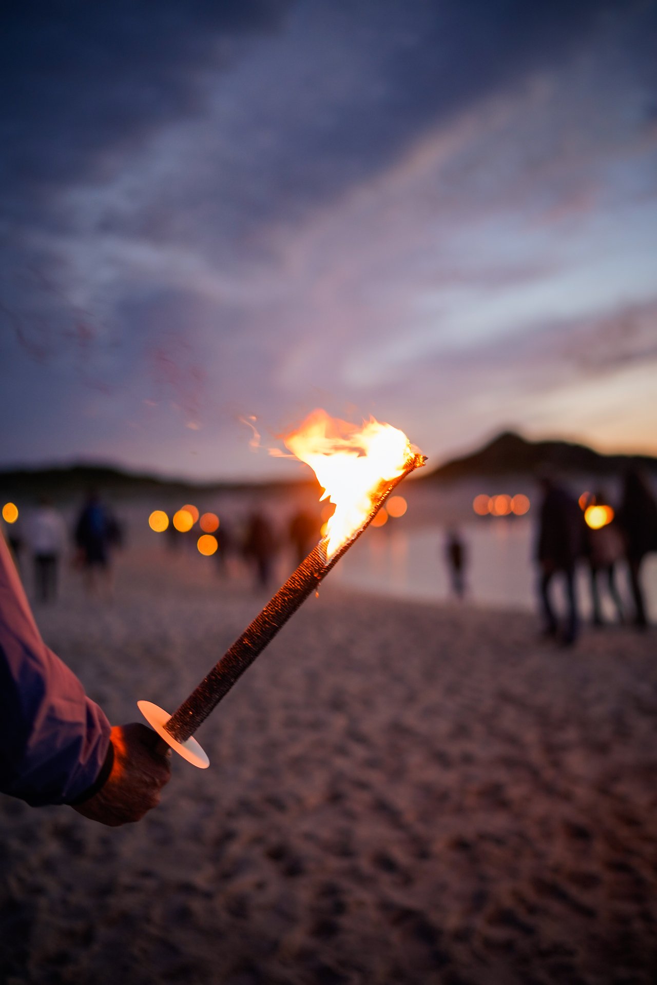 Eine lodernde Fackel am Strand des Söl’ring Hof Sylt in der Abenddämmerung.