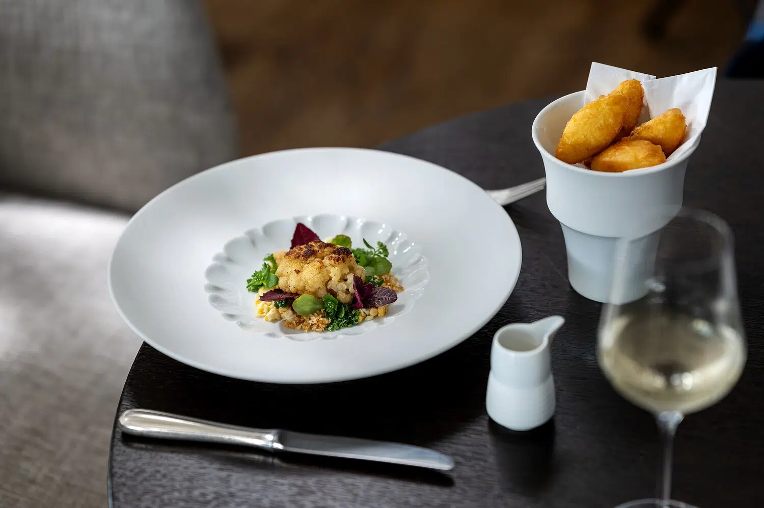 Ein eleganter Fischteller mit Gemüse, Pommes frites, Wein und Besteck daneben.